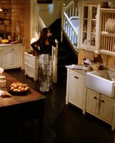 a woman standing in a kitchen next to a table with food on top of it