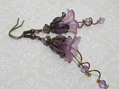 IRIDESCENT LILAC FLOWER EARRINGS ▪️▪️▪️▪️▪️▪️▪️️▪️▪️▪️▪️▪️▪️ These pretty pale purple bohemian dangle earrings are made with super cute Lucite fairy flowers. They have matching coloured crystals in a delicate lilac for beautiful sparkle when they move. They are finished with antique bronze fish hook ear wires and ornate floral bead caps. They are very light weight and are perfect for special occasions, festivals and bridesmaids yet cute enough for everyday wear. 💜MATERIALS *Lucite Flowers *Anti Lilac Earrings, Fairy Earrings, Lucite Flowers, Vintage Inspired Earrings, Hippie Flowers, Bronze Earrings, Hippie Earrings, Purple Earrings, Lilac Flowers