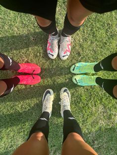 four people standing in a circle with their feet on each other's ankles and wearing running shoes