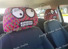 two crocheted hats sitting in the back seat of a car with faces drawn on them