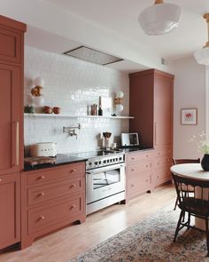 a kitchen with pink cabinets and white tile backsplash, an area rug on the floor