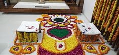 a large flower arrangement in the middle of a room with other flowers on the floor