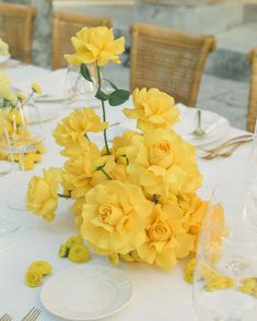 the table is set with yellow flowers and place settings