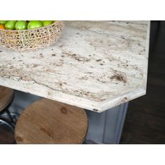 a bowl of fruit sitting on top of a table next to two stools and a counter