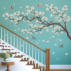 this is an image of a tree with white flowers and birds flying around it on the wall