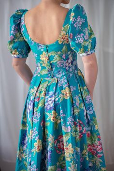 Buy 3 items and get 30% off your entire order. Limited offer. All orders are shipped via FedEx. Shipping to the US typically takes 2 to 3 business days, while within the EU, it takes 2 to 6 business days. Fabulous vintage Laura Ashley dress, crafted from vibrant turquoise cotton with a colorful floral pattern in shades of pink, green, and purple. This stunning piece is designed with a fitted bodice and a flared, pleated skirt that falls to mid-calf length. It features charming short puff sleeves Laura Ashley Dress, Puff Sleeve Blouse, Laura Ashley, Style Expert, Fitted Bodice, Fit And Flare Dress, Pleated Skirt, Floral Dress, Dress Clothes For Women