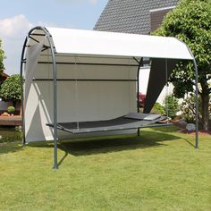 a white tent with a black bed in the grass