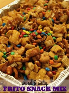 a tin pan filled with snack mix on top of a wooden table