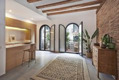 an open living room and dining area with arched doors leading to the balcony, potted plants in vases