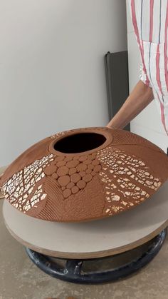 a person standing next to a brown vase on top of a white table with holes in it