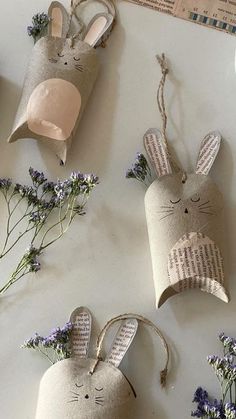 three little bunnies made out of newspaper are sitting next to some lavender flowers and twine