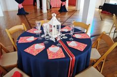 the table is set for an event with blue linens and orange napkins on it