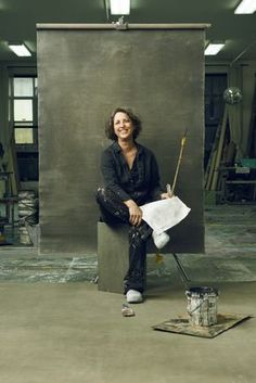 a woman sitting on top of a box next to a paint brush and paper towel