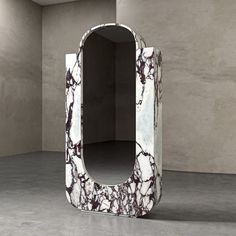 an unusual white and black marbled mirror in a room with concrete walls on either side