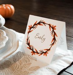 an empty card sitting on top of a table next to some plates and pumpkins