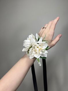 a woman's hand holding a white flower on top of a black chair arm