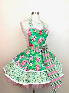 a green apron dress with pink flowers on it and a bow tie around the waist