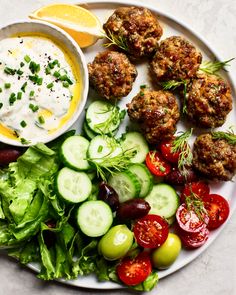 a white plate topped with meatballs and veggies next to a bowl of ranch dressing