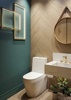 a white toilet sitting next to a sink in a bathroom under a wooden mirror mounted on the wall