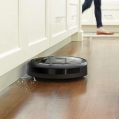 a person walking past a roomba on the floor in front of a kitchen door