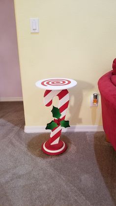 a red chair sitting next to a white table with a candy cane on top of it