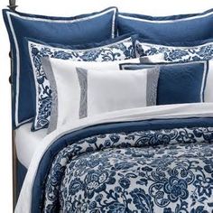 a bed with blue and white comforters on it