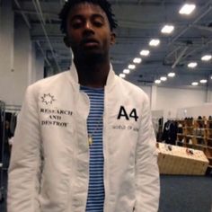 a man in a white jacket and blue striped shirt is standing in an empty room