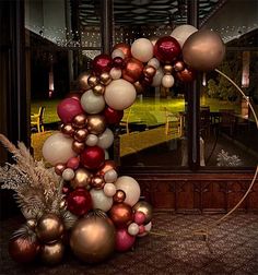 a christmas wreath made out of balloons and ornaments in front of a window with lights