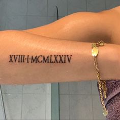 a woman's arm with roman numerals on it and a gold chain