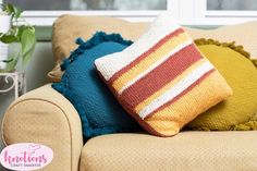 a couch with two pillows on it next to a potted plant and a window