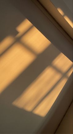 an orange clock sitting on top of a wooden table next to a window with the sun shining through it