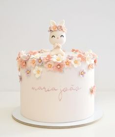 a white cake decorated with flowers and an animal figurine sitting on top of it