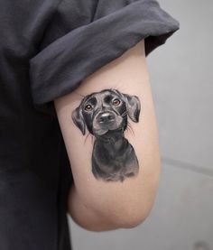 a black dog tattoo on the right inner arm and shoulder, with an orange eye