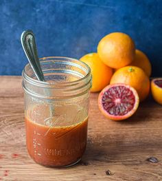 a mason jar filled with brown liquid next to some grapefruits