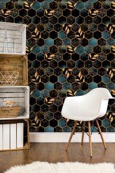 a white chair sitting in front of a wall covered in hexagonal tiles and gold leaves