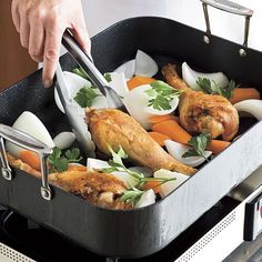 a person cooking chicken and vegetables in a pan