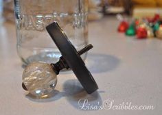 a glass jar with a black handle and a hair clip on it sitting on a counter