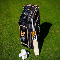 a cricket bat and glove laying on the ground next to it's case in grass