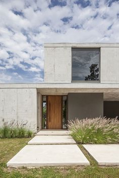 a concrete house with grass and plants in the front yard