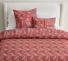 a red paisley bed spread with two pillows