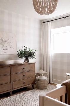 a baby's room with a crib, dresser and window in the background