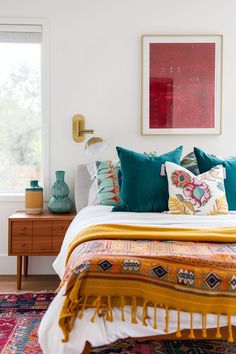 a bed with colorful pillows and blankets on it