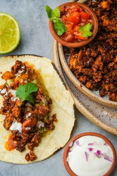 two tortillas with meat, salsa and sour cream are on the table next to each other