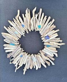 a wreath made out of driftwood with blue glass beads on the center and sides