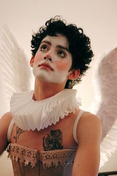 a woman with white makeup and wings on her chest