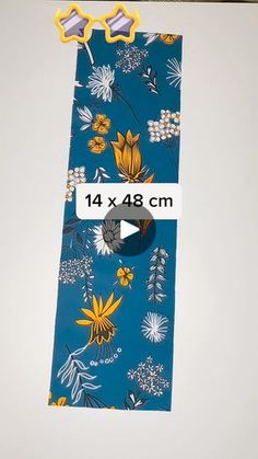 a blue tie with yellow and white flowers on it, sitting next to a ruler