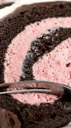 a piece of chocolate cake with pink frosting on it and a fork in the middle