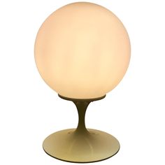 a white ball light sitting on top of a metal stand with an oval shape base