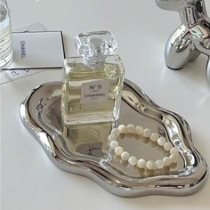 a bottle of perfume sitting on top of a silver tray next to a faucet