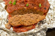 meatloaf sandwich with tomato sauce and green onions on foil wrapped in tinfoil